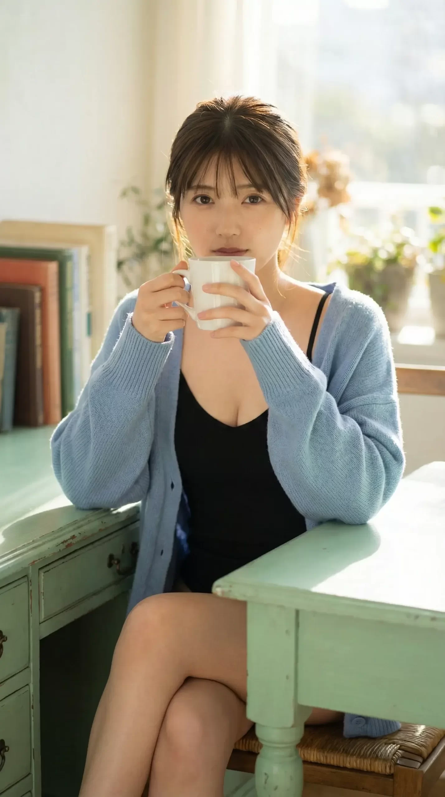 女性がマグカップを手に持ち、コーヒーを飲んでいる