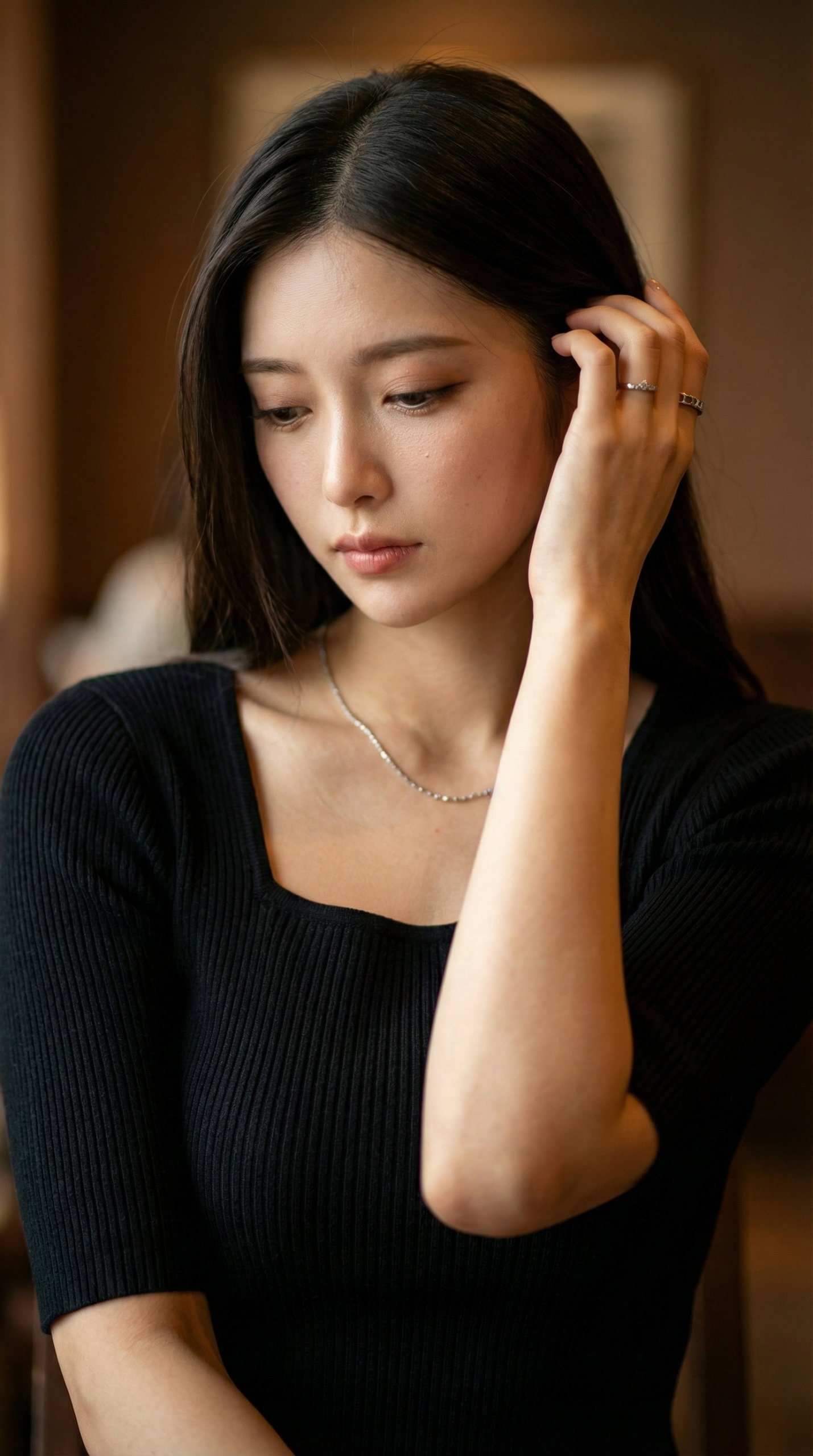 黒の服を着て髪を触る女性