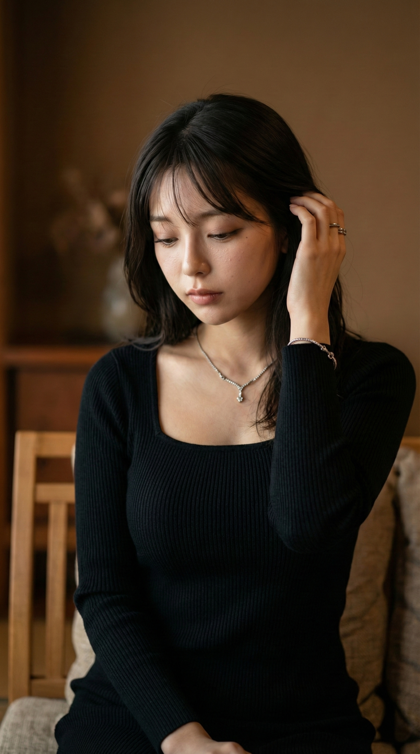 黒い服を着て髪に触れる女性