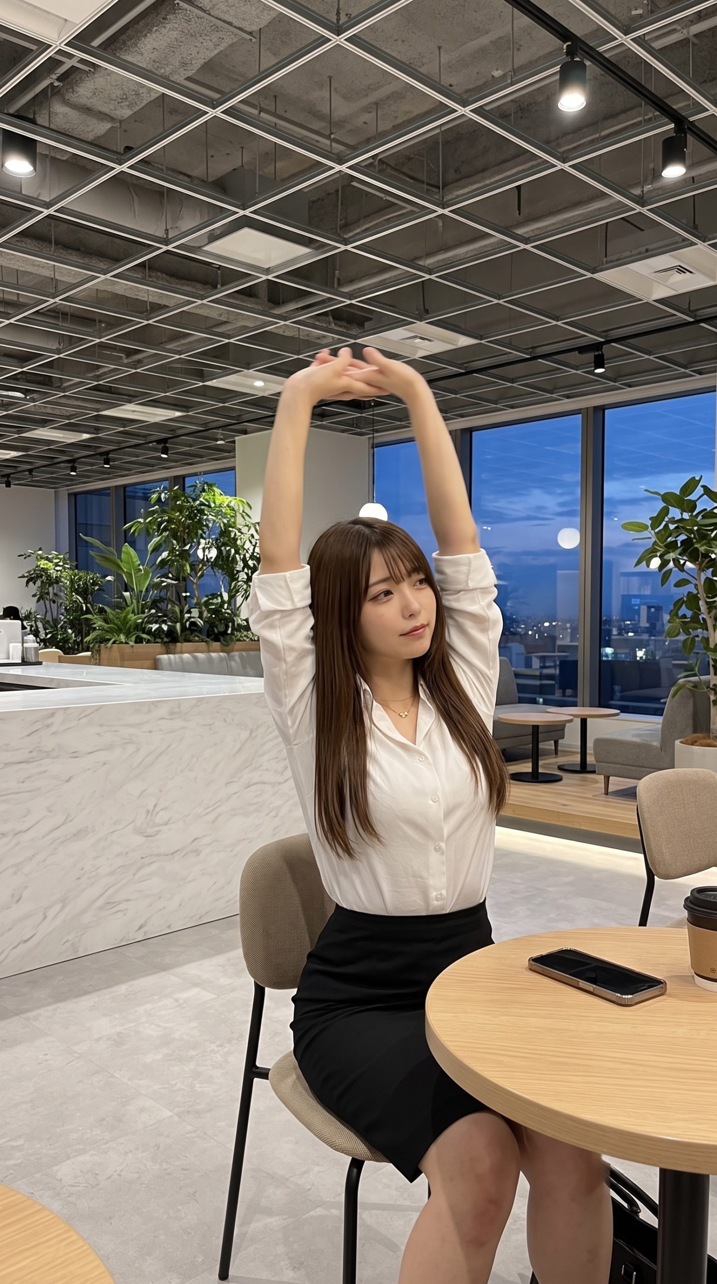 オフィスで椅子に座り、両腕を上に伸ばしてストレッチをする女性