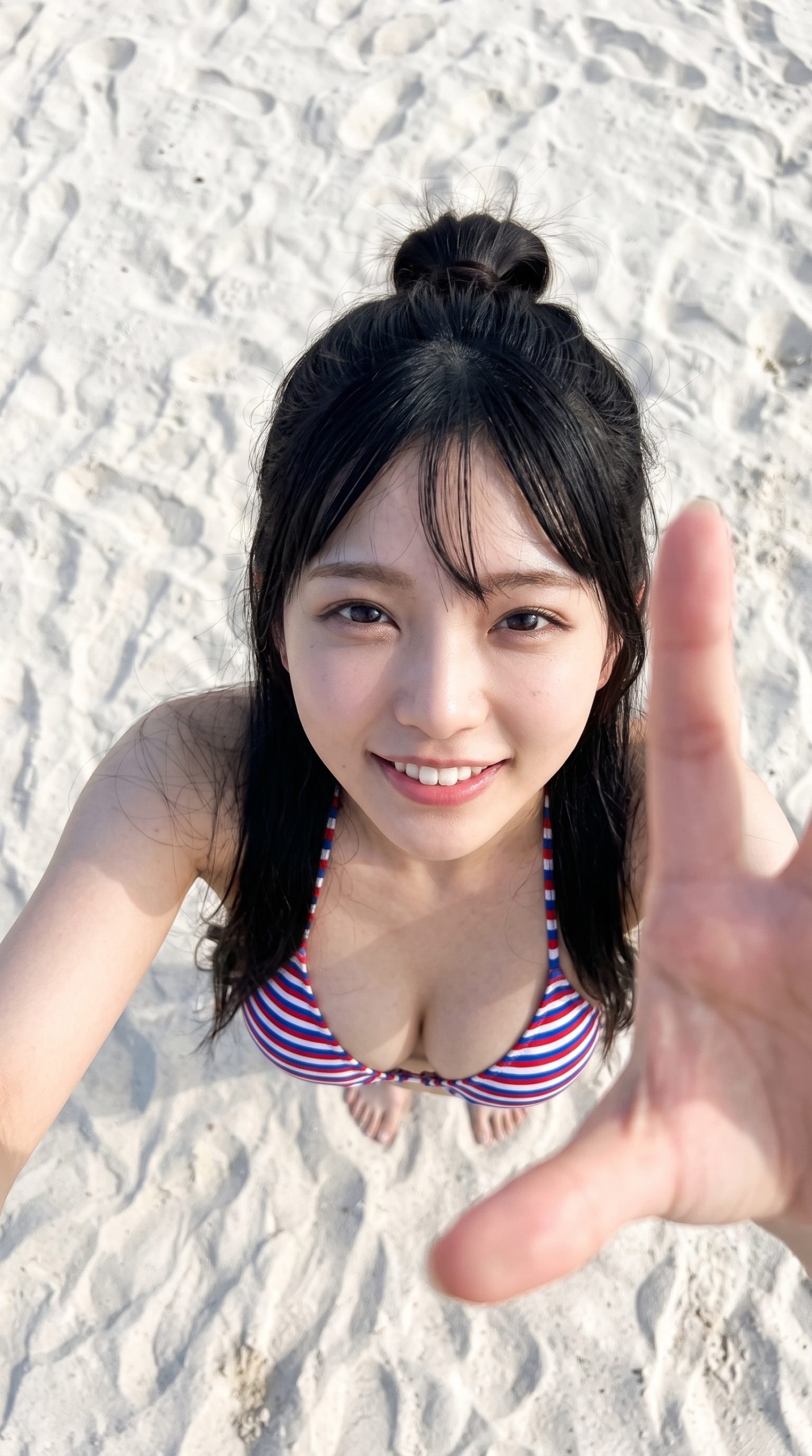 白い砂浜でボーダー柄の水着を着て、笑顔でカメラに手を伸ばす女性