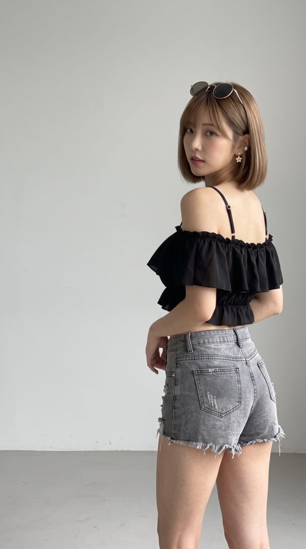 黒のフリルキャミソールとデニムショートパンツを着用し振り返る女性