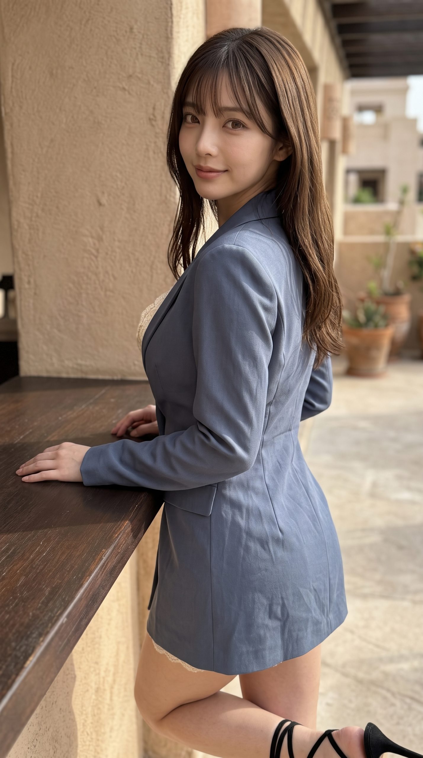 青いジャケットを着用し、屋外のカウンターに寄り添うロングヘアの女性。