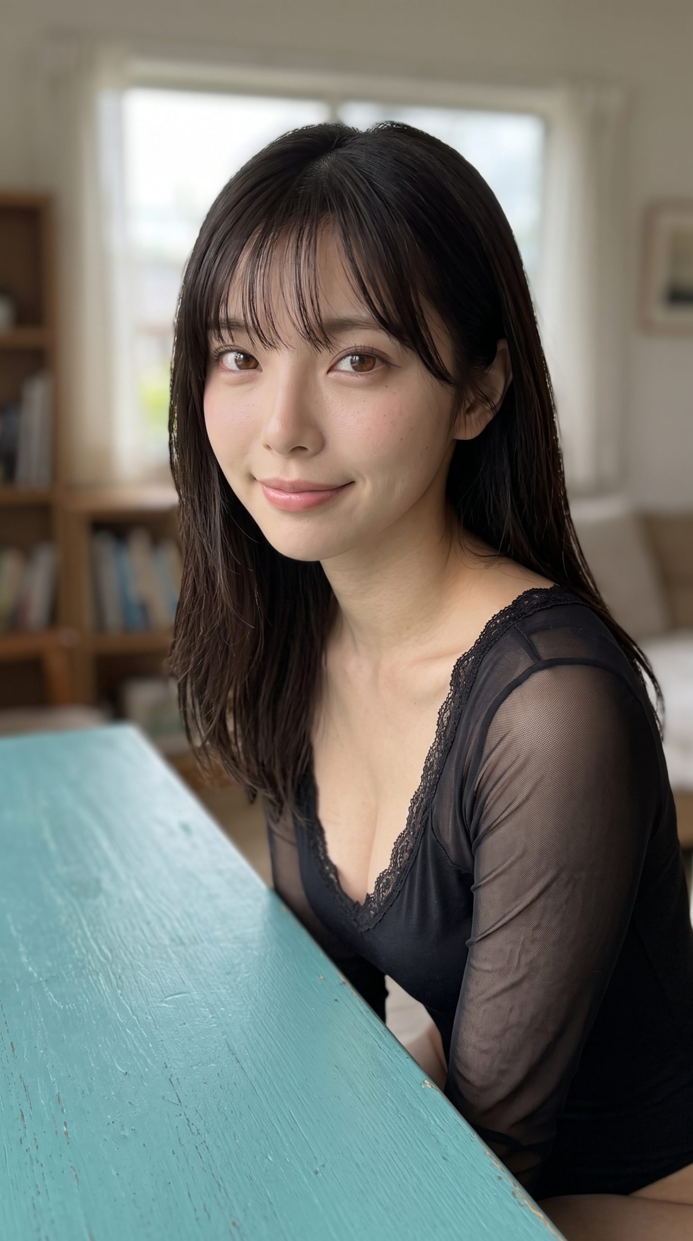 黒いトップスを着て、室内で微笑んでいる、ロングヘアの女性のポートレート。
